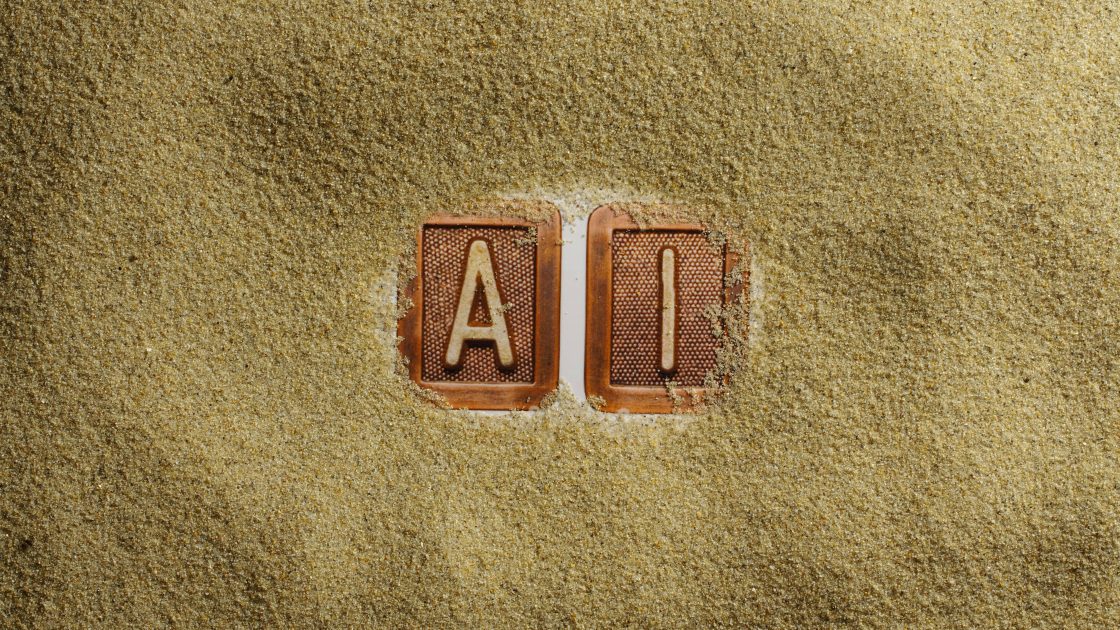 Image of letters: AI in sand