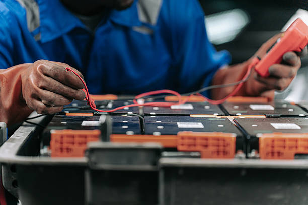 A technician diagnosing a lithium ion car battery during electric vehicle maintenance. The image illustrates servicing procedures and battery diagnostics techniques in an auto repair environment.